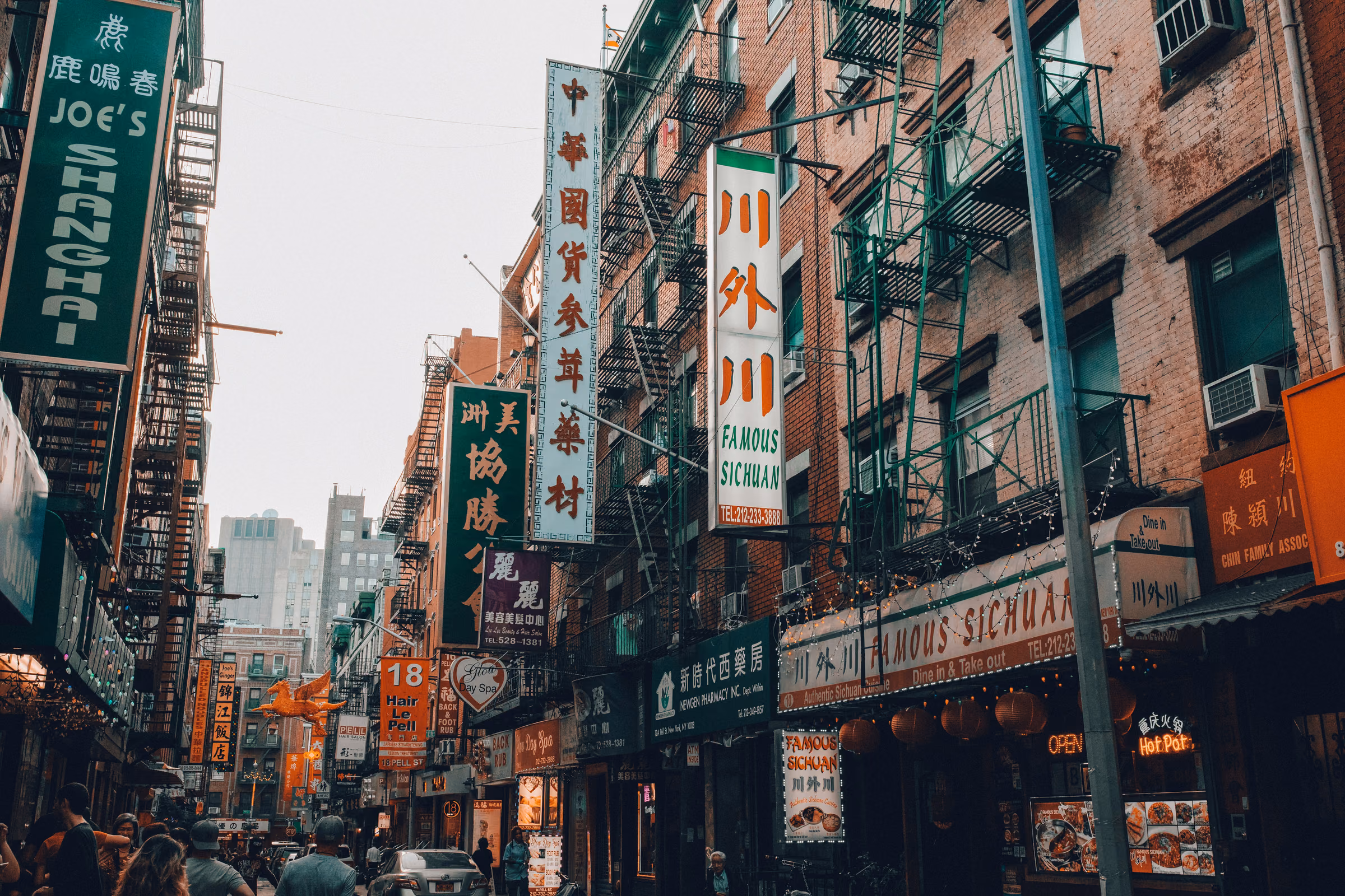 Chinese shop signs and brick buildings on a street in Chinatown, Manhattan.