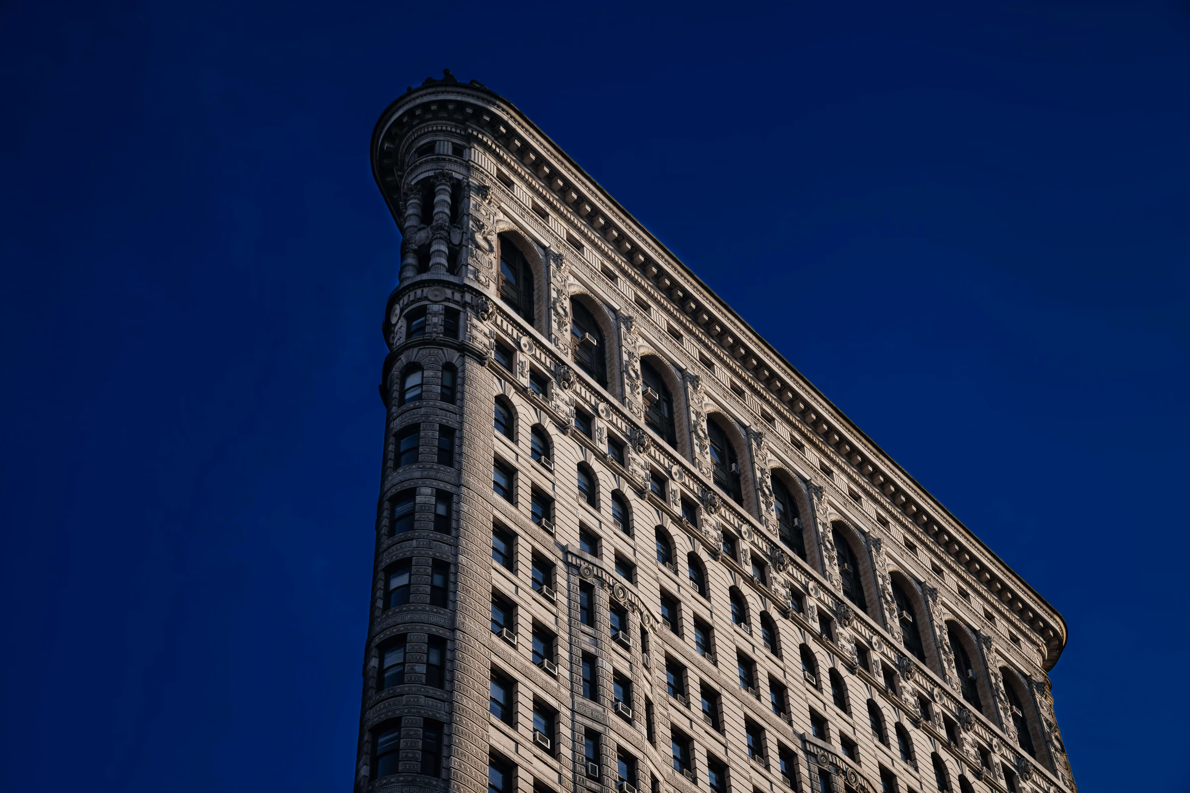 The Flatiron Building against a deep blue sky