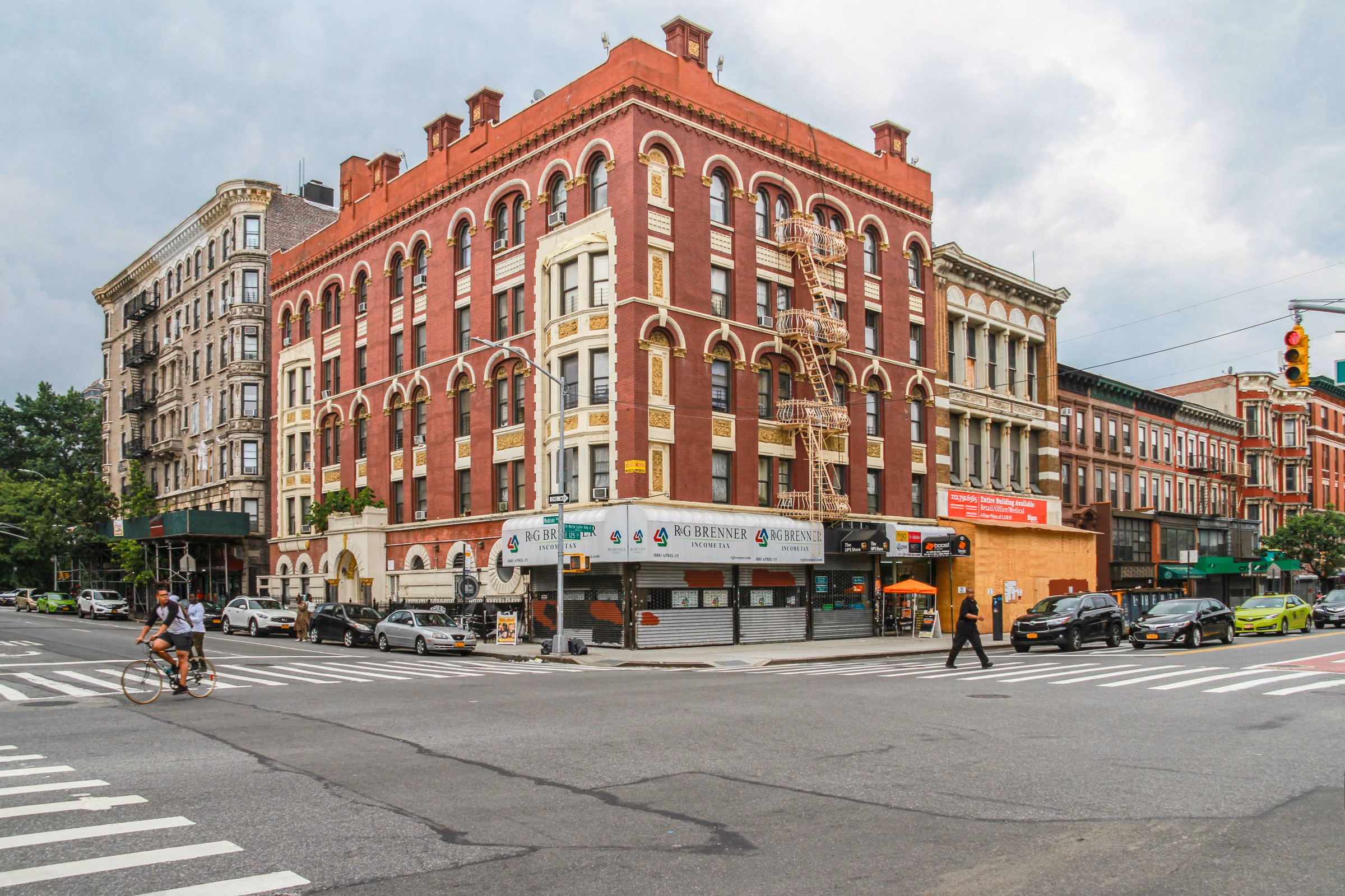 Historic red-brick corner buildings along a Harlem street in Manhattan.