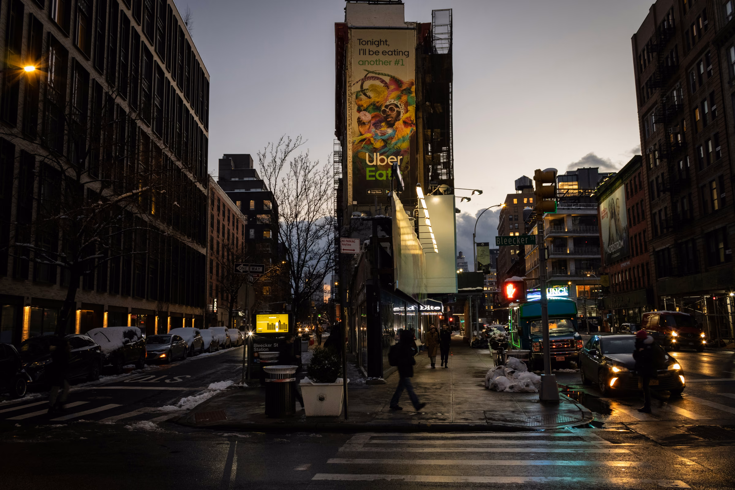 A wet intersection and historic buildings in NoHo, Manhattan, at dusk.